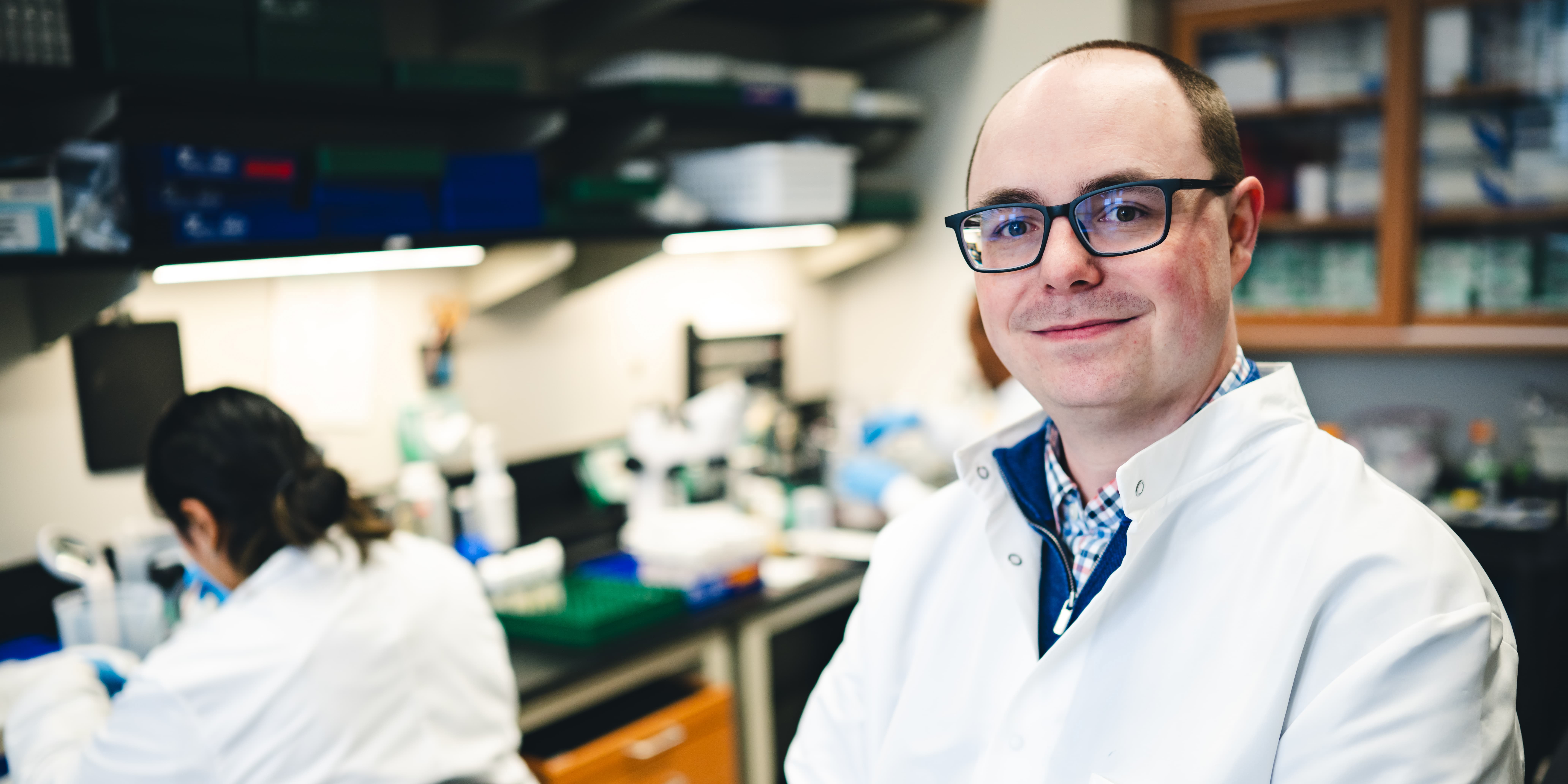 Dylan Shropshire, assistant professor of biological sciences in his lab smiling.