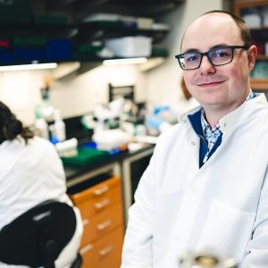 Dylan Shropshire, assistant professor of biological sciences in a lab smiling.