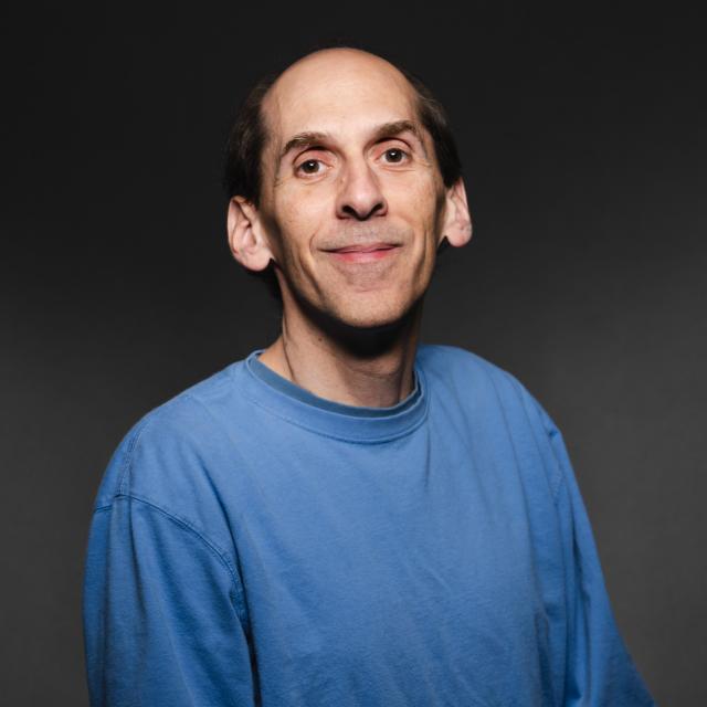 Jeff Trimarchi wearing a blue long sleeve t-shirt smiling for his headshot.